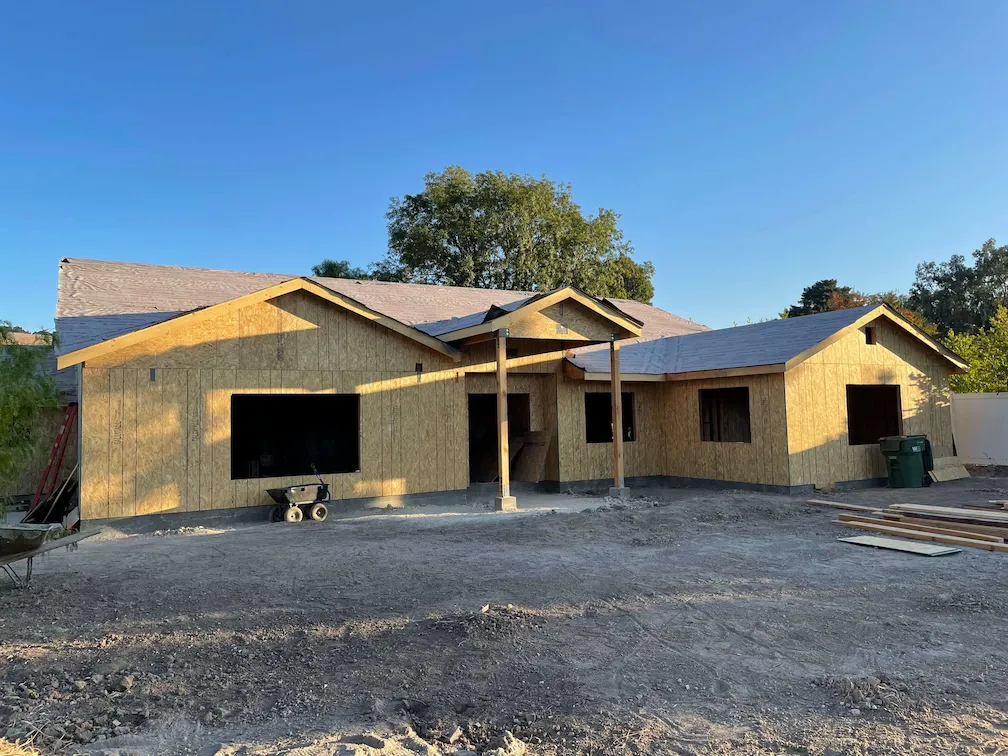 Partially completed house with wooden framing nearly finished.