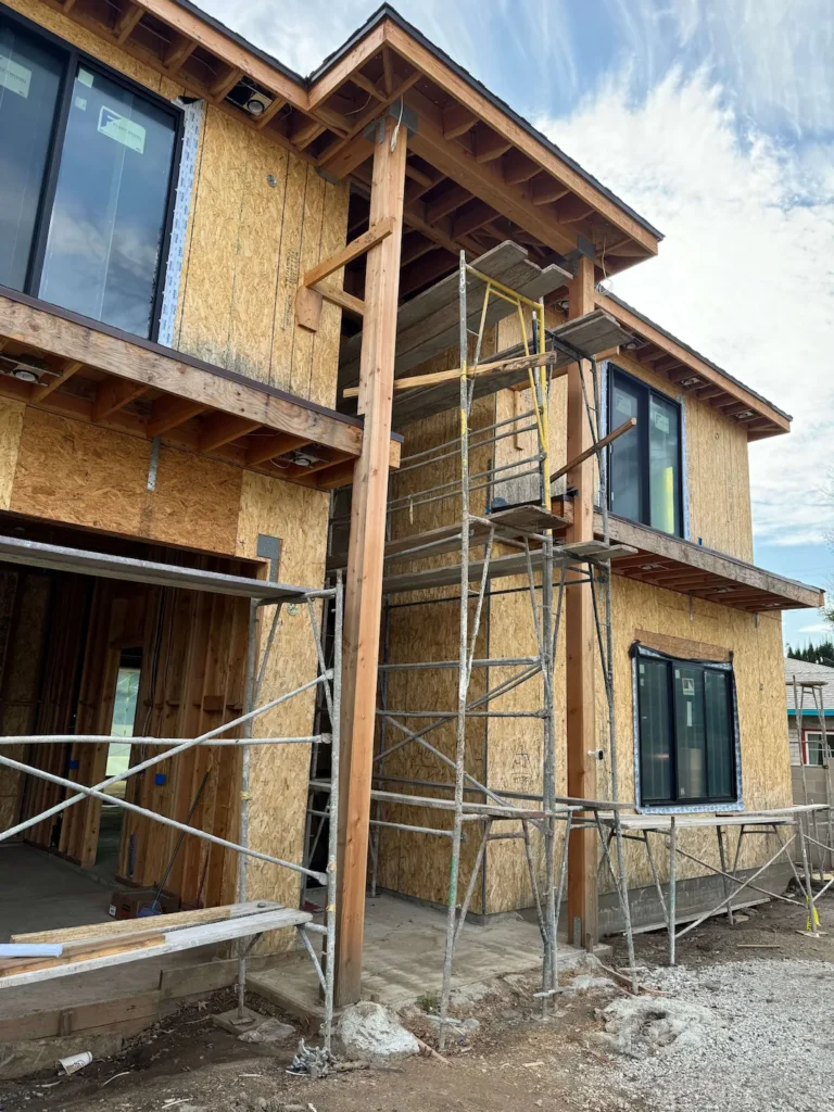 Two-story house framing in progress with windows already installed.
