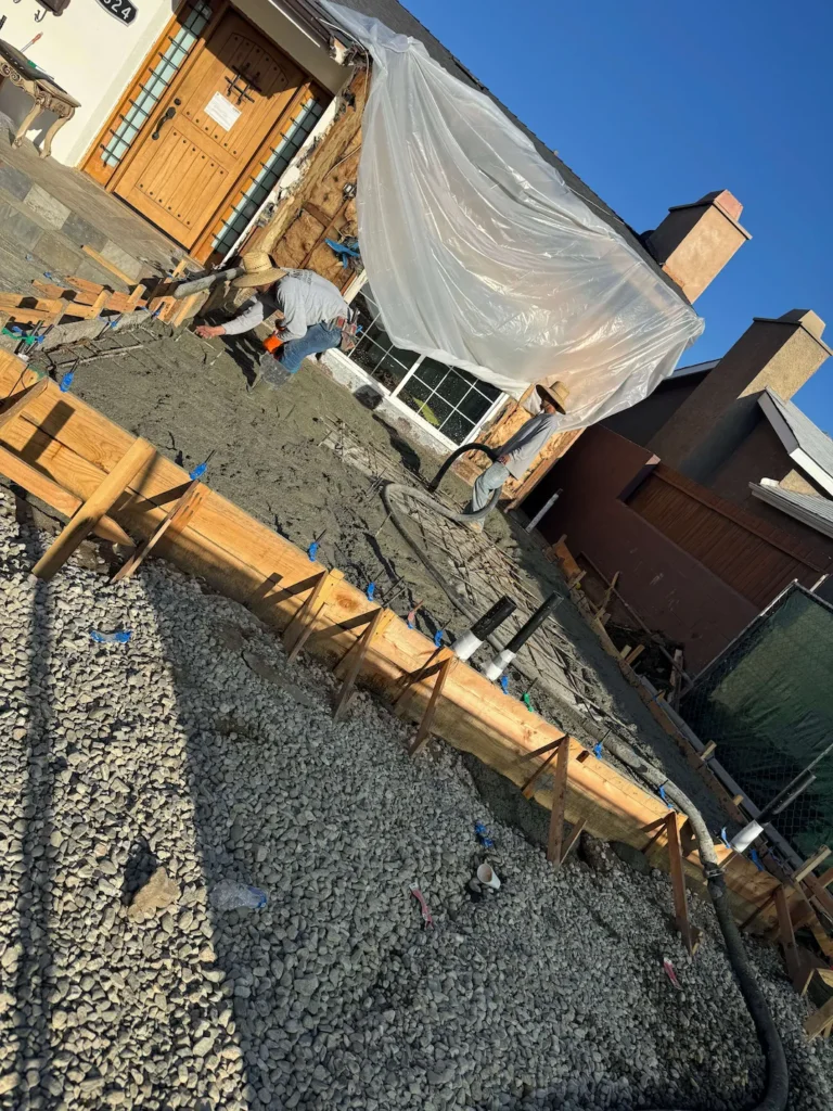 Construction workers pouring and leveling fresh cement for a new surface.