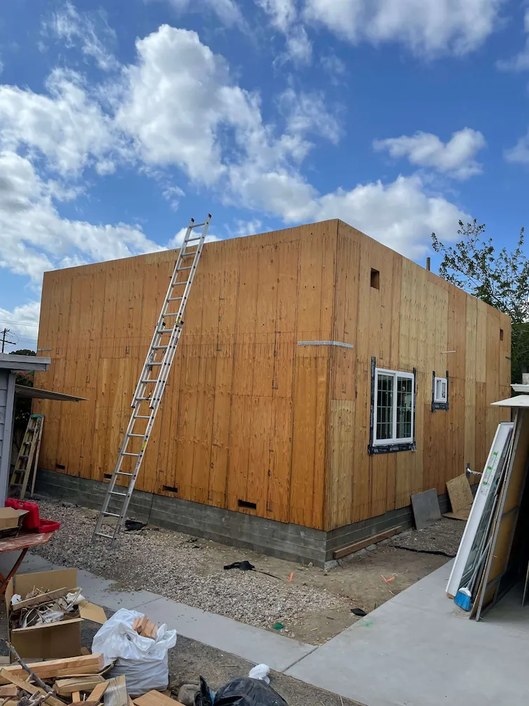 ADU with completed framing and installed windows, with a ladder leaning against it.