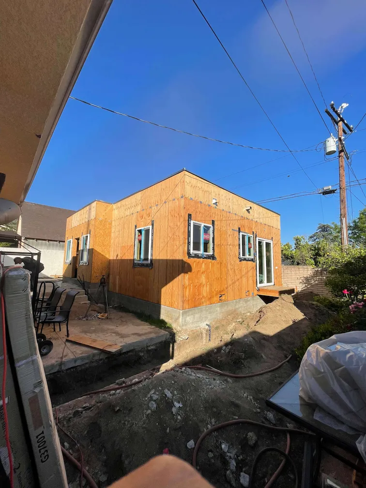ADU with completed framing and installed windows, surrounded by dirt and cement.