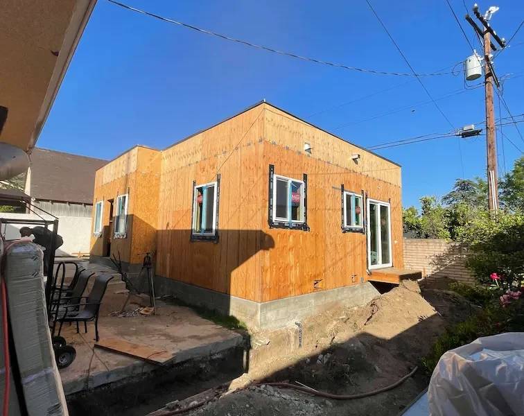 ADU with completed framing and installed windows, surrounded by dirt and cement.